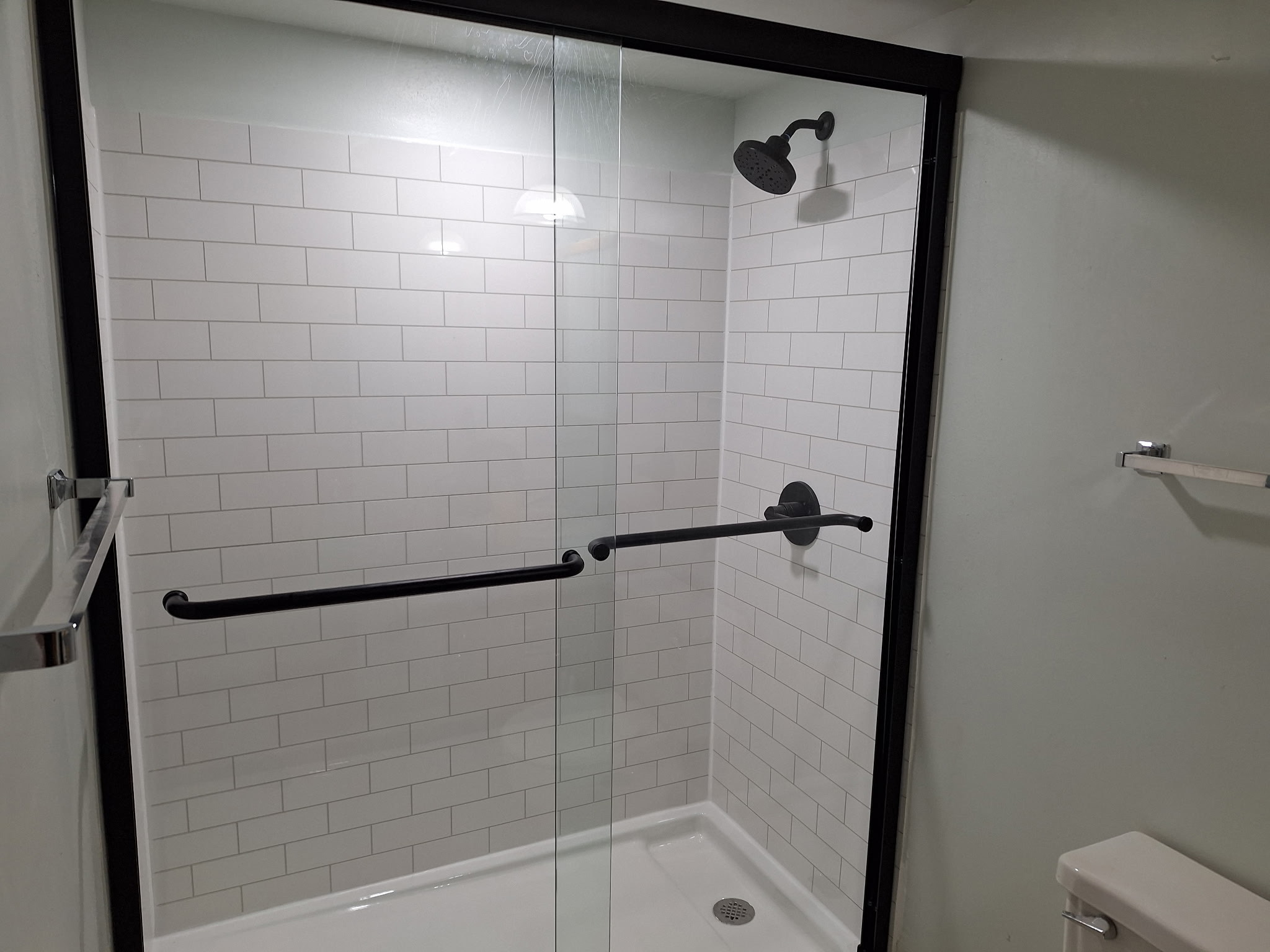 Walk-in shower with glass doors, white subway tile, and matte black fixtures