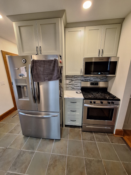 Kitchen with light cabinets, stainless steel refrigerator and gas range, tiled backsplash, and tiled floor